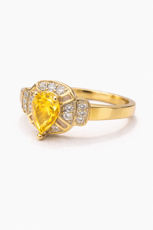 Gold ring with a yellow gemstone on a white background