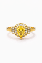 Gold ring with a yellow gemstone and diamond accents on a white background