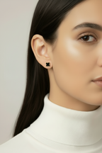 Close-up of a person wearing a black floral earring against a neutral background