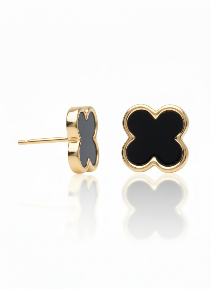 Gold earrings with black heart-shaped stones on a white background