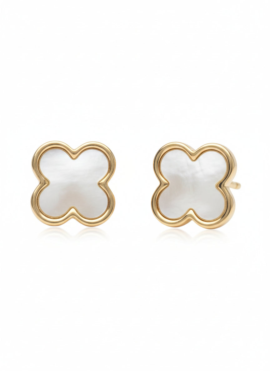Pair of champagne gold four-leaf clover stud earrings with white mother-of-pearl inlay centres photographed on soft white background, showing polished metallic finish, symmetrical clover design with four rounded petals, and delicate refined craftsmanship