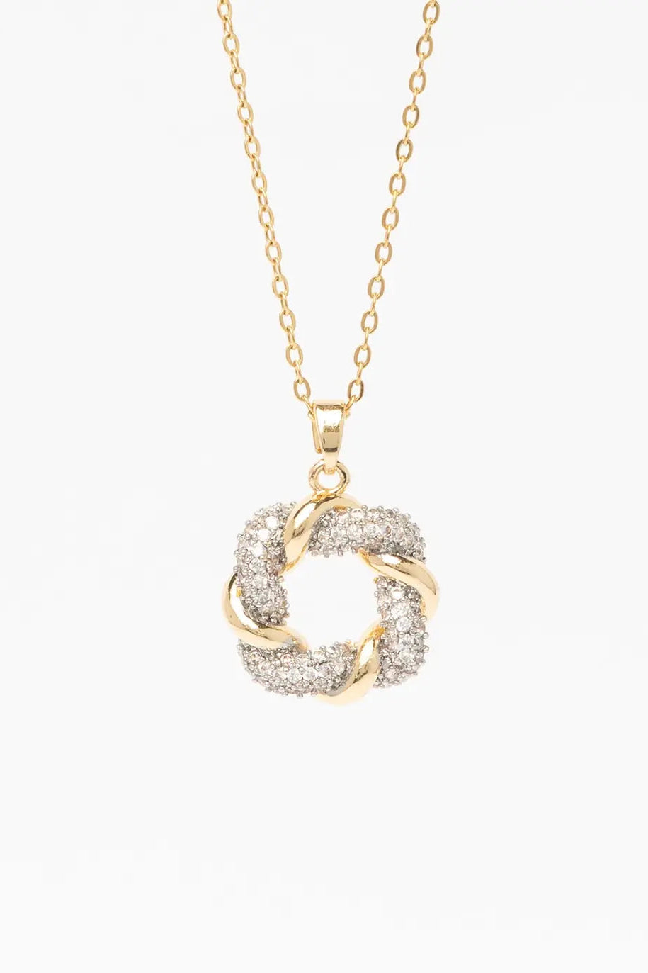 Close-up of champagne gold diamond knot pendant necklace on model showing intricate knot design with pavé crystal detailing, delicate thin chain, polished metallic finish against natural skin tones with soft lighting