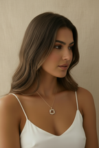 Woman wearing a white top and necklace against a beige background
