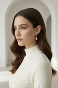 Woman with a stylish hairdo wearing a white outfit against a neutral background