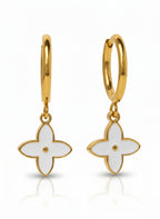 Gold hoop earrings with white flower-shaped charms on a white background