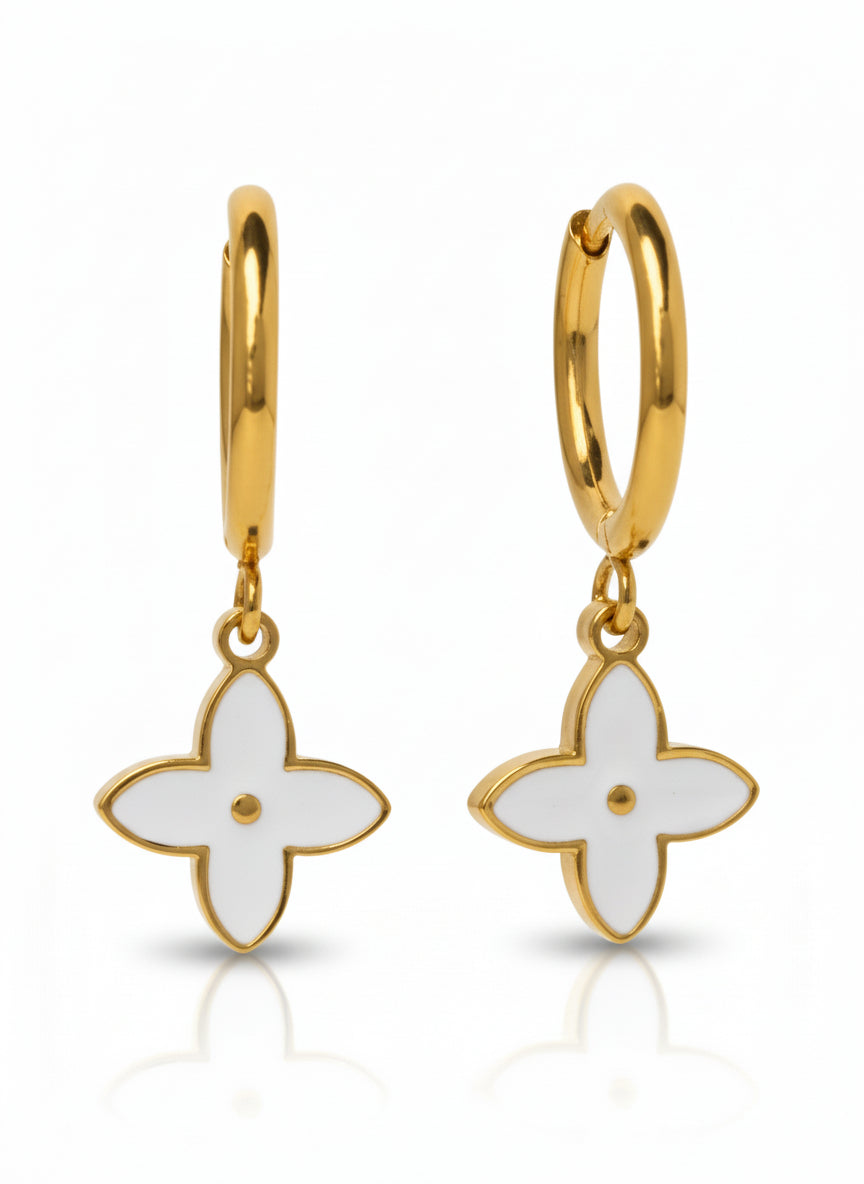 Gold hoop earrings with white flower-shaped charms on a white background