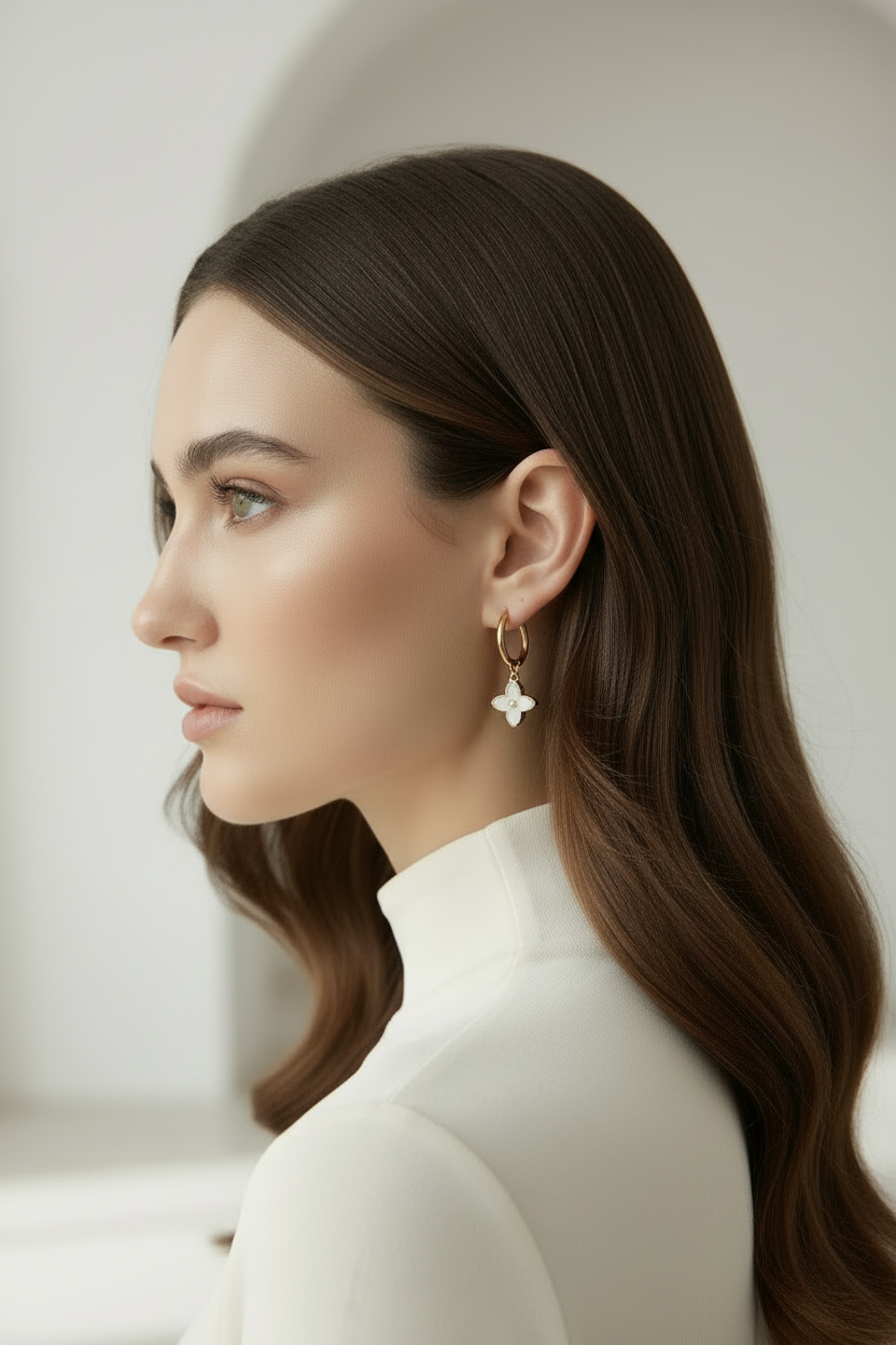 Woman with long brown hair wearing a white turtleneck and star-shaped earrings against a neutral background