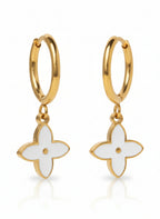 Gold hoop earrings with white flower-shaped charms on a white background