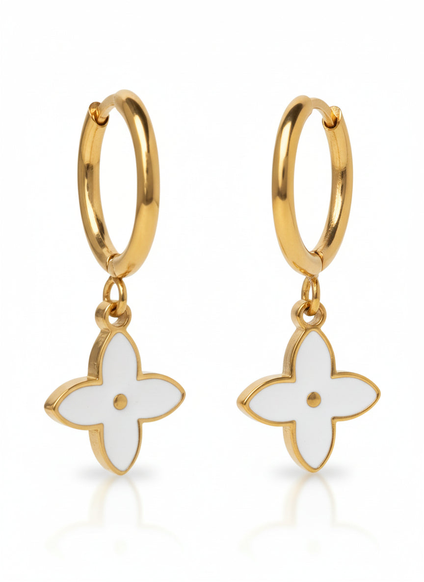 Gold hoop earrings with white flower-shaped charms on a white background