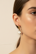 Close-up of a person wearing gold hoop earrings with a neutral background