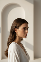 Half-Inlay Clover Hoop Earrings- Gold hoop earrings champagne gold-tone four-leaf clover motif lifestyle shot worn on model against neutral background, ZARIÉ fine jewellery SÉRÉNITÉ collection