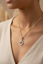 Gold necklace with a diamond pendant on a model against a neutral background