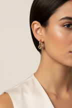 Close-up of a woman wearing gold hoop earrings against a neutral background