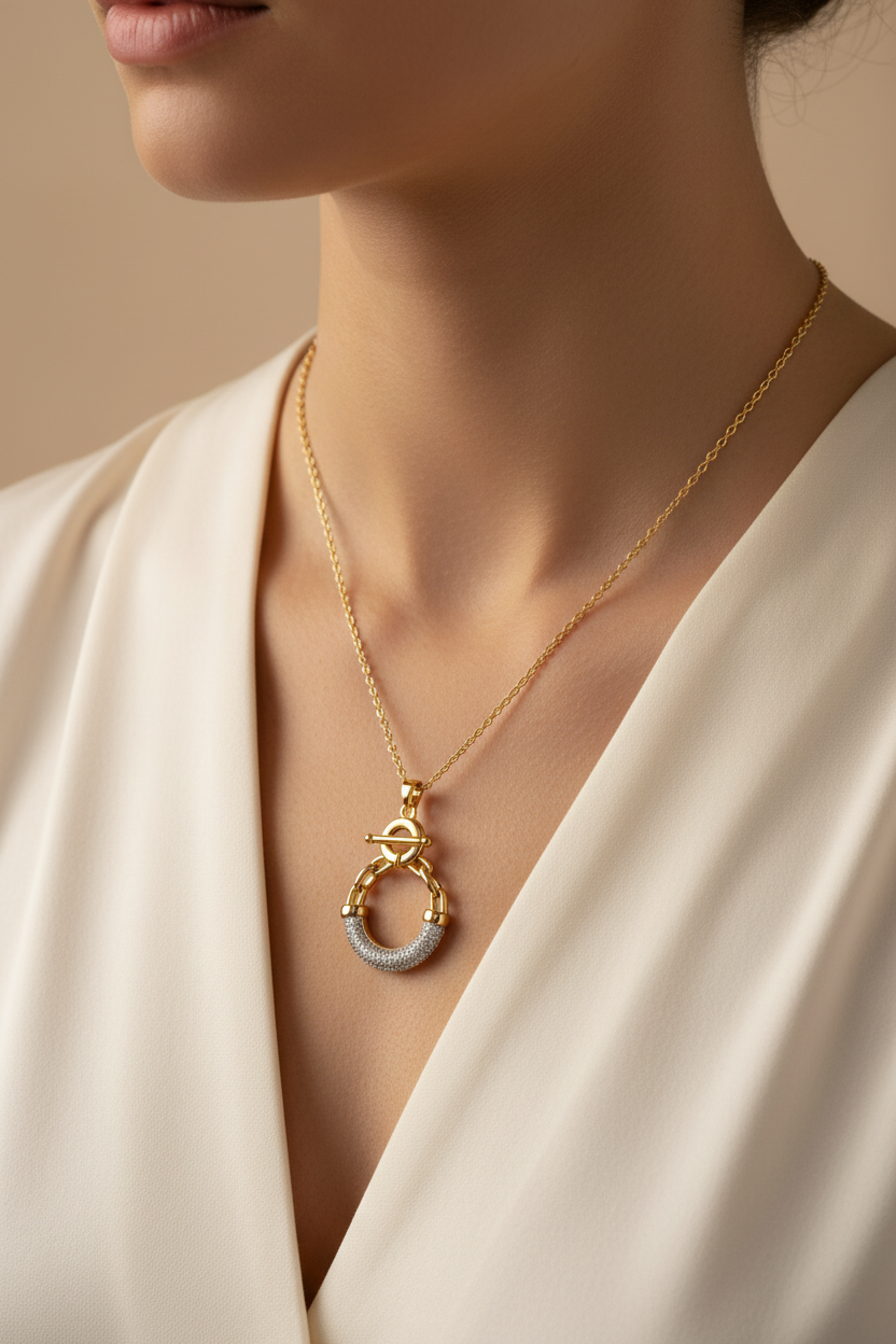 Gold necklace with a pendant on a person wearing a white garment.