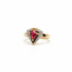 Close-up of champagne gold red stone halo ring showing deep red gemstone surrounded by delicate pavé crystal border, refined band design with polished finish against natural skin tones