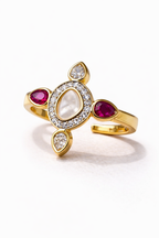 Gold ring with red gemstones and a central pearl on a white background