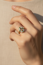 Close-up of a hand wearing a decorative ring on a neutral background