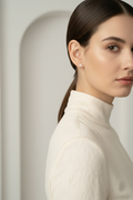 Woman wearing a white turtleneck sweater with a neutral background