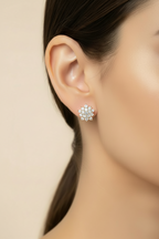 Close-up of a person wearing a floral silver earring against a beige background