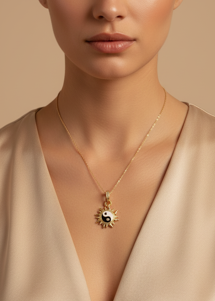 Gold necklace with a yin yang pendant worn by a model against a beige background