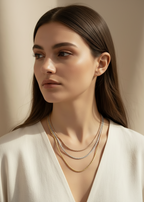 Woman wearing layered tri-tone twisted chain necklace set in rose gold, silver and champagne gold against neutral beige background, delicate minimal jewellery styling with three different length chains creating refined layered composition, soft natural lighting with warm undertones