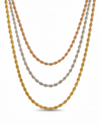Three twisted chain necklaces in rose gold, silver and champagne gold tones laid flat on soft beige linen background, showing varying chain lengths and polished metallic finishes, ultra-thin minimal design with refined craftsmanship and warm beige aesthetic

