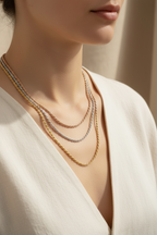 Close-up of woman wearing tri-tone twisted necklace set layered on neck, showing rose gold, silver and champagne gold chains in different lengths against natural skin tones, delicate refined craftsmanship with soft lighting highlighting the polished metallic finish and minimal elegant design