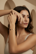 Woman wearing gold bracelets on a neutral background