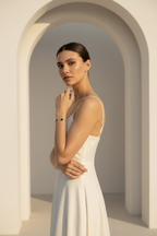 Woman in a white dress standing in an archway with a neutral background