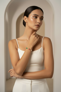 Woman wearing a white top and colorful bracelet in a neutral setting